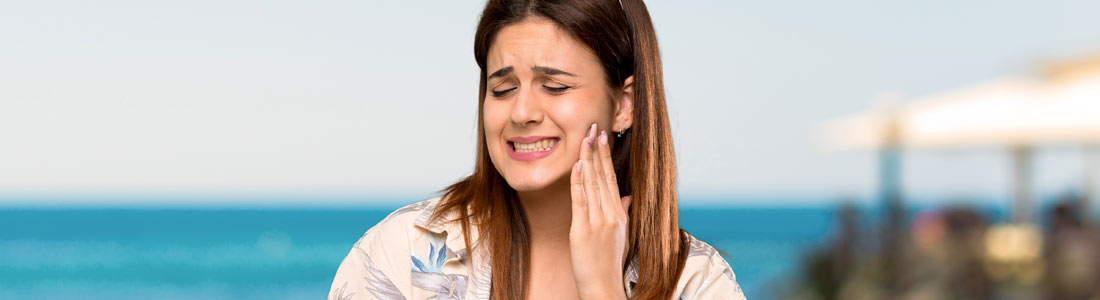 mujer en la playa con dolor de muelas
